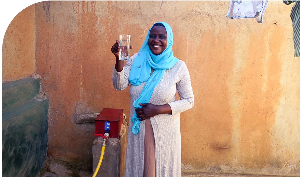 Woman holding a glass of safe, clear drinking water, Water Access Rwanda. Mighty Ally Institute